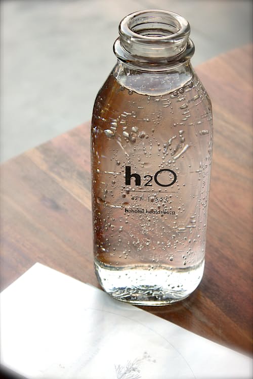une carafe d'eau de la marque de l'hôtel placée sur un bureau avec un mot