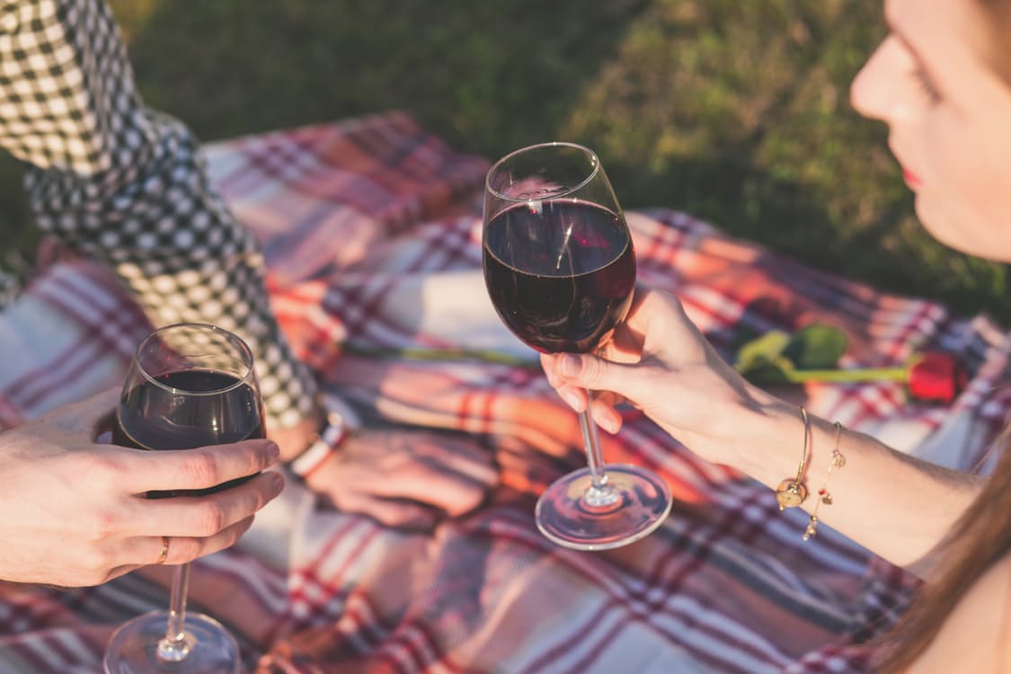 a couple shares wine during a picnic