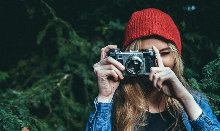 a woman with a red beanie and an old 35mm camera