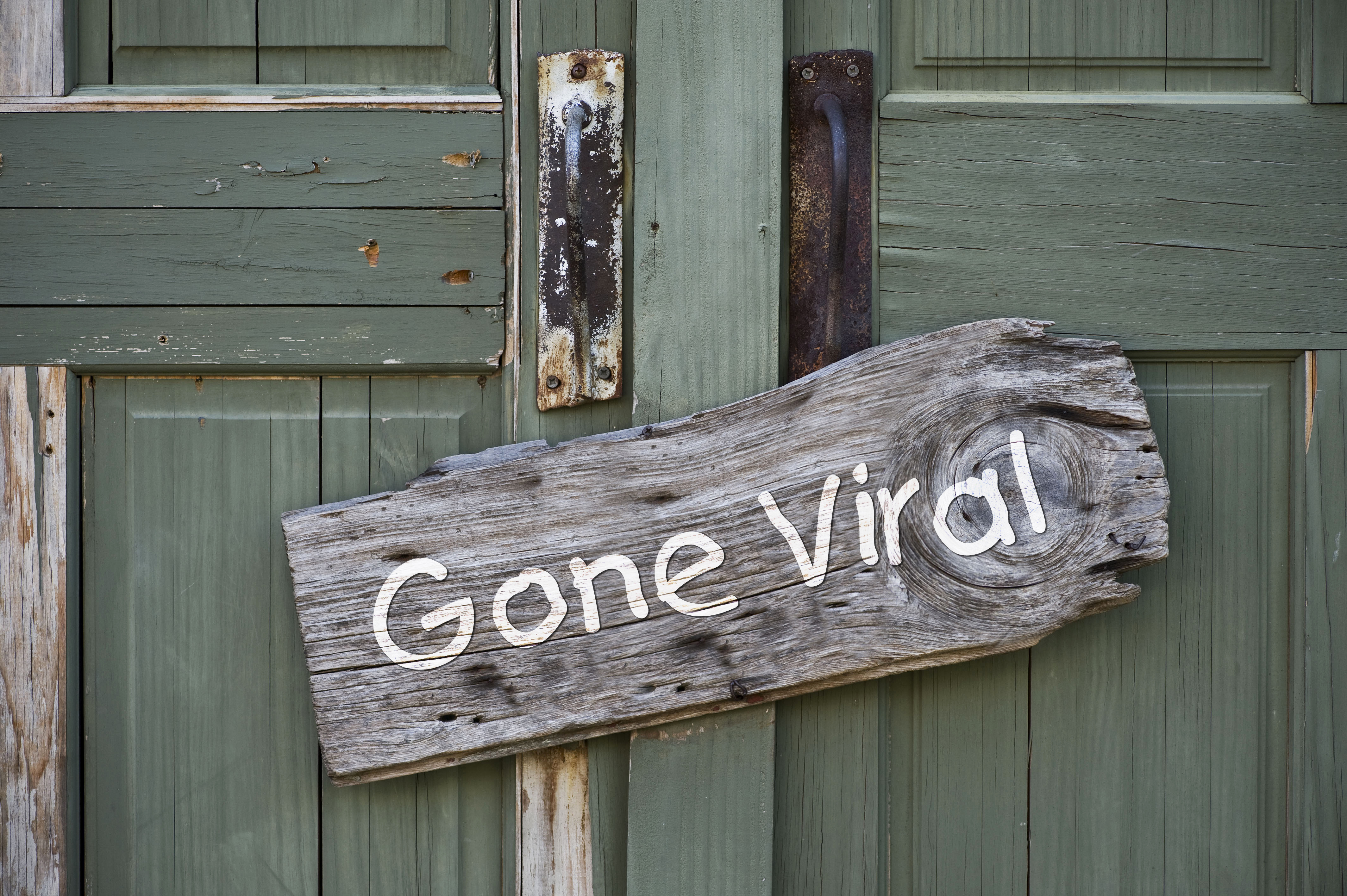La porte en bois turquoise d'un B&B avec un signe "Gone Viral"